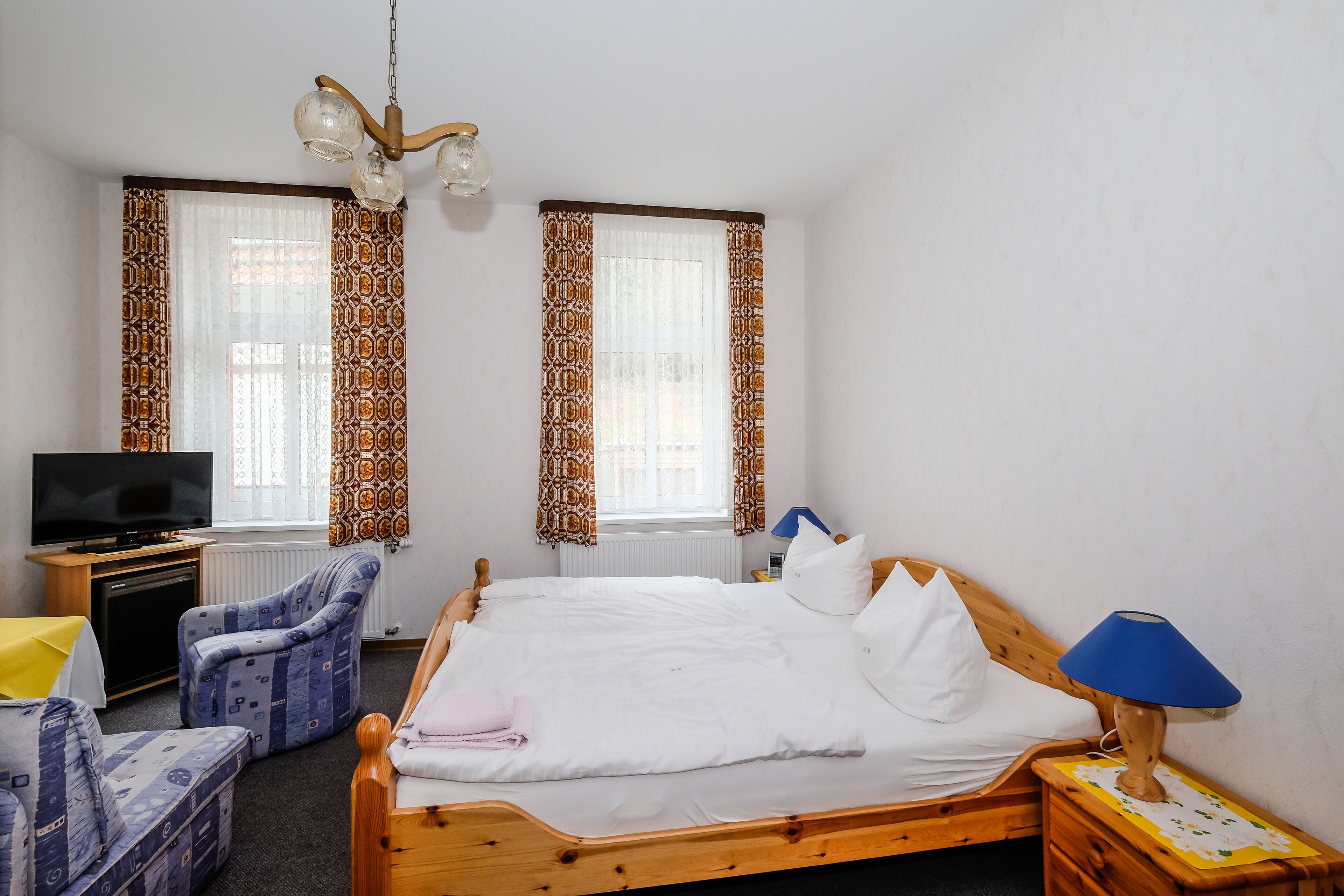 Una habitación de hotel con una cama de madera, un televisor, una silla y una lámpara.