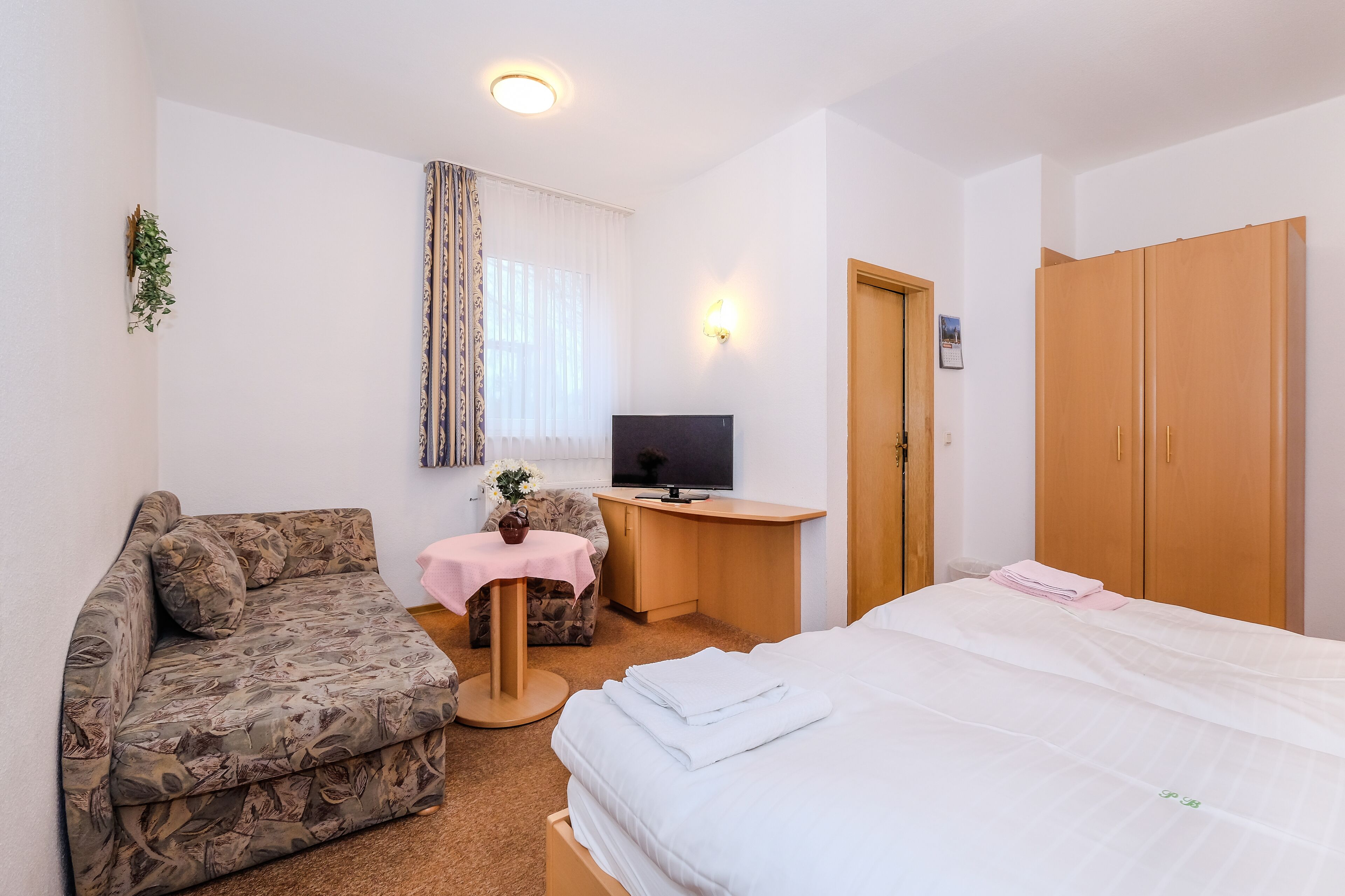 Une chambre d’hôtel comprenant un lit, un canapé, un bureau avec une télévision et une armoire.