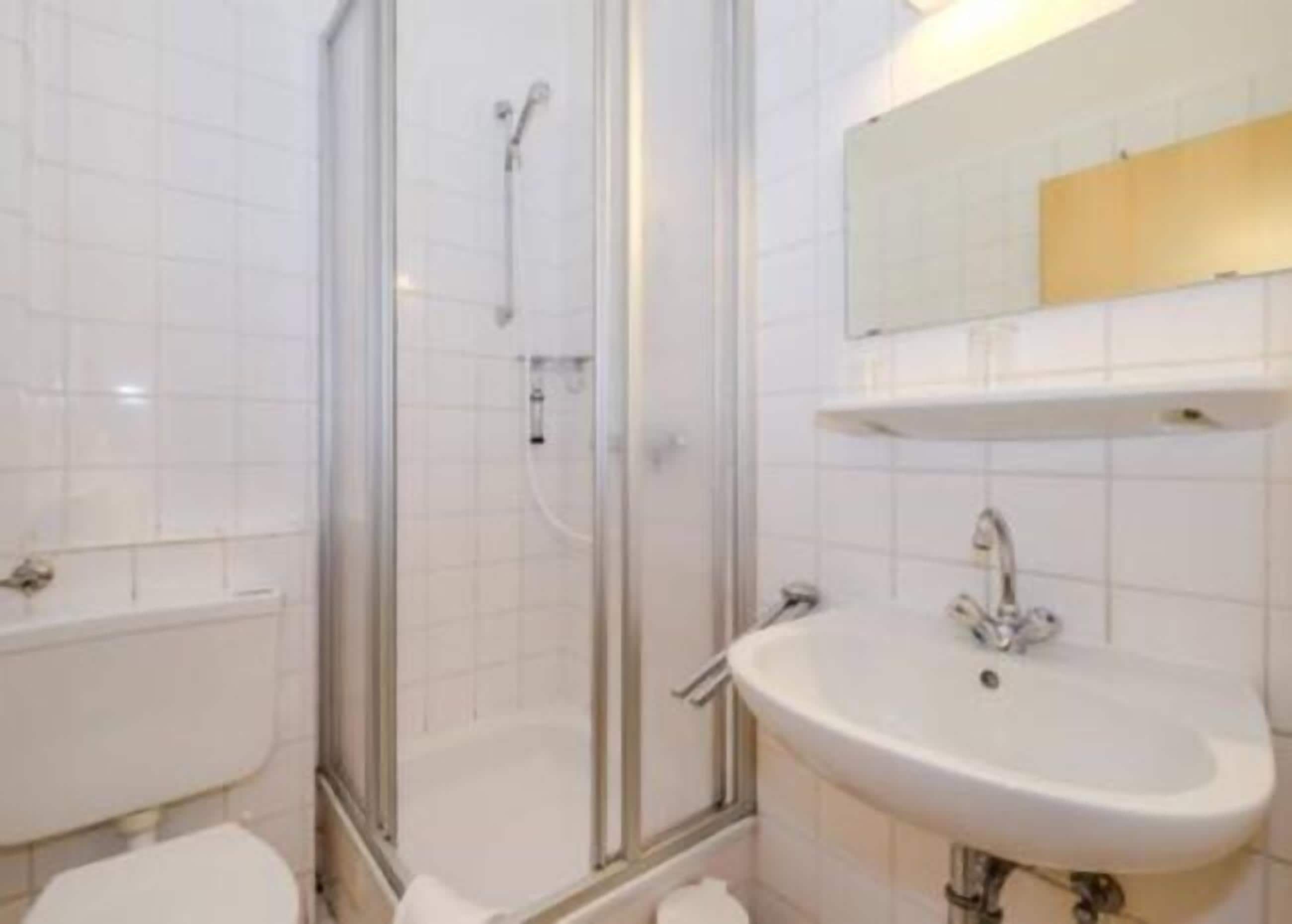 A bathroom with a glass-enclosed shower, a sink, and a mirror above the sink.