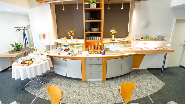 A reception area with a curved counter, multiple seating options, and a variety of amenities including a plant, a clock, and a display of food items.
