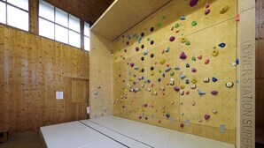A climbing gym with wooden walls and a climbing wall with various holds.