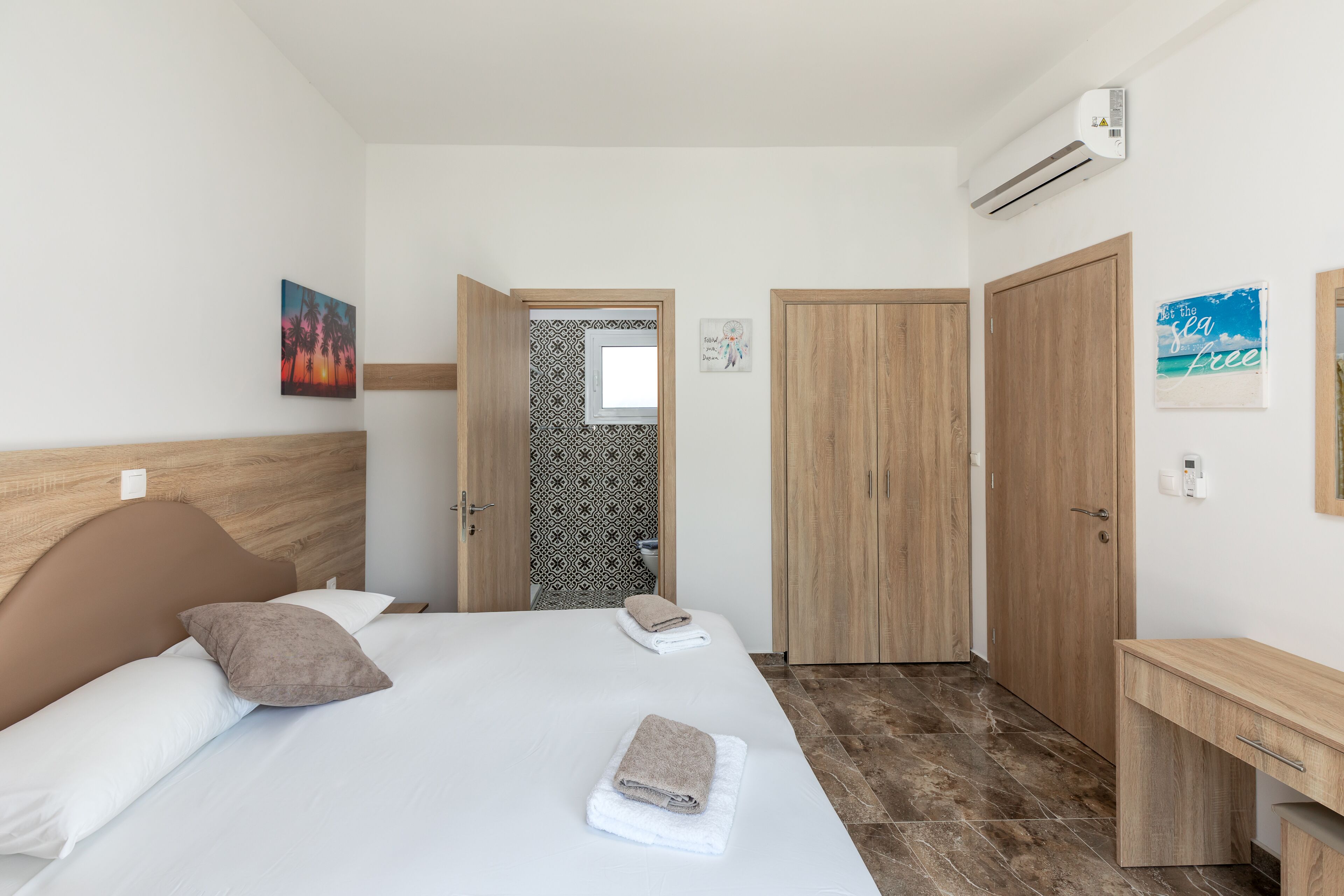 Hotellihuone, jossa on sänky, yöpöytä, vaatekaappi ja ilmastointilaite.