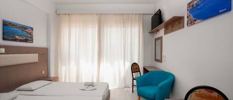 Quarto de hotel com duas camas, uma escrivaninha, uma cadeira, televisão e obras de arte nas paredes.