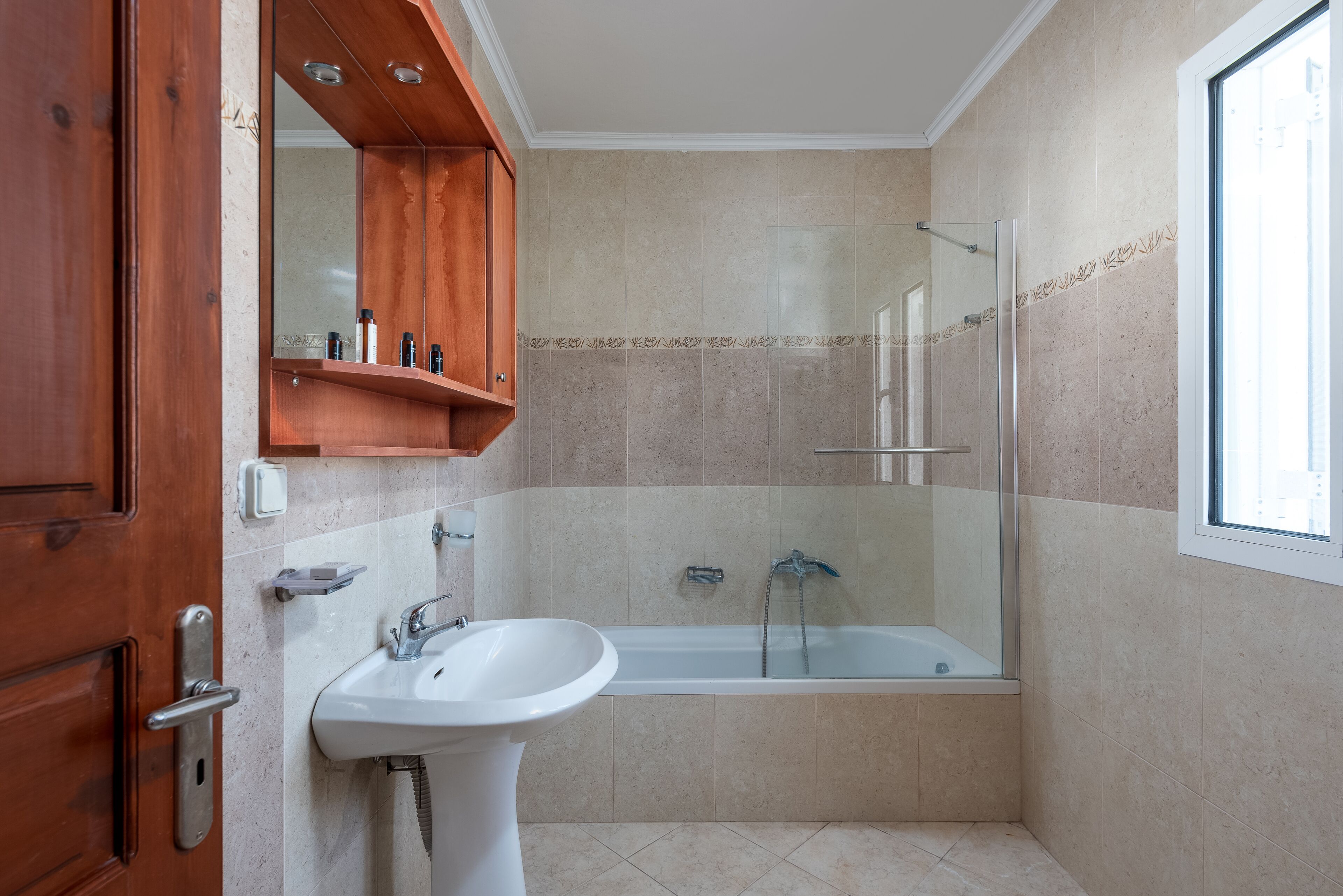 A bathroom with a bathtub, a sink, and a glass shower enclosure.