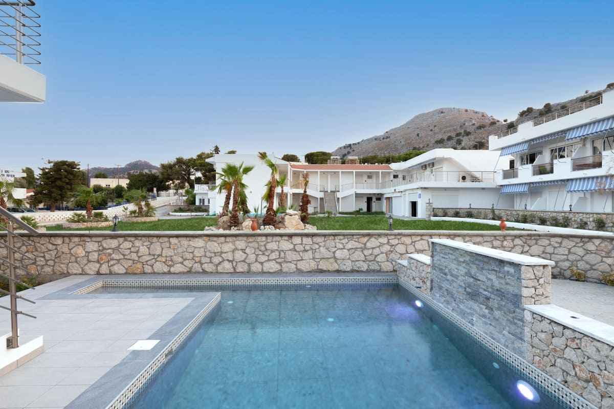 Una piscina con pared de piedra y vistas de los edificios y el paisaje circundante.
