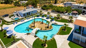 A swimming pool with sun loungers and umbrellas, surrounded by a landscaped garden and a view of the countryside. - Paradise Garden (Rhodes)