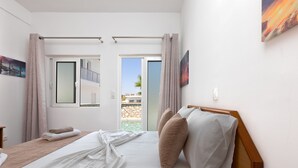 A hotel room with a bed, two windows, a door, and a view of the outside. - Paradise Garden (Rhodes)