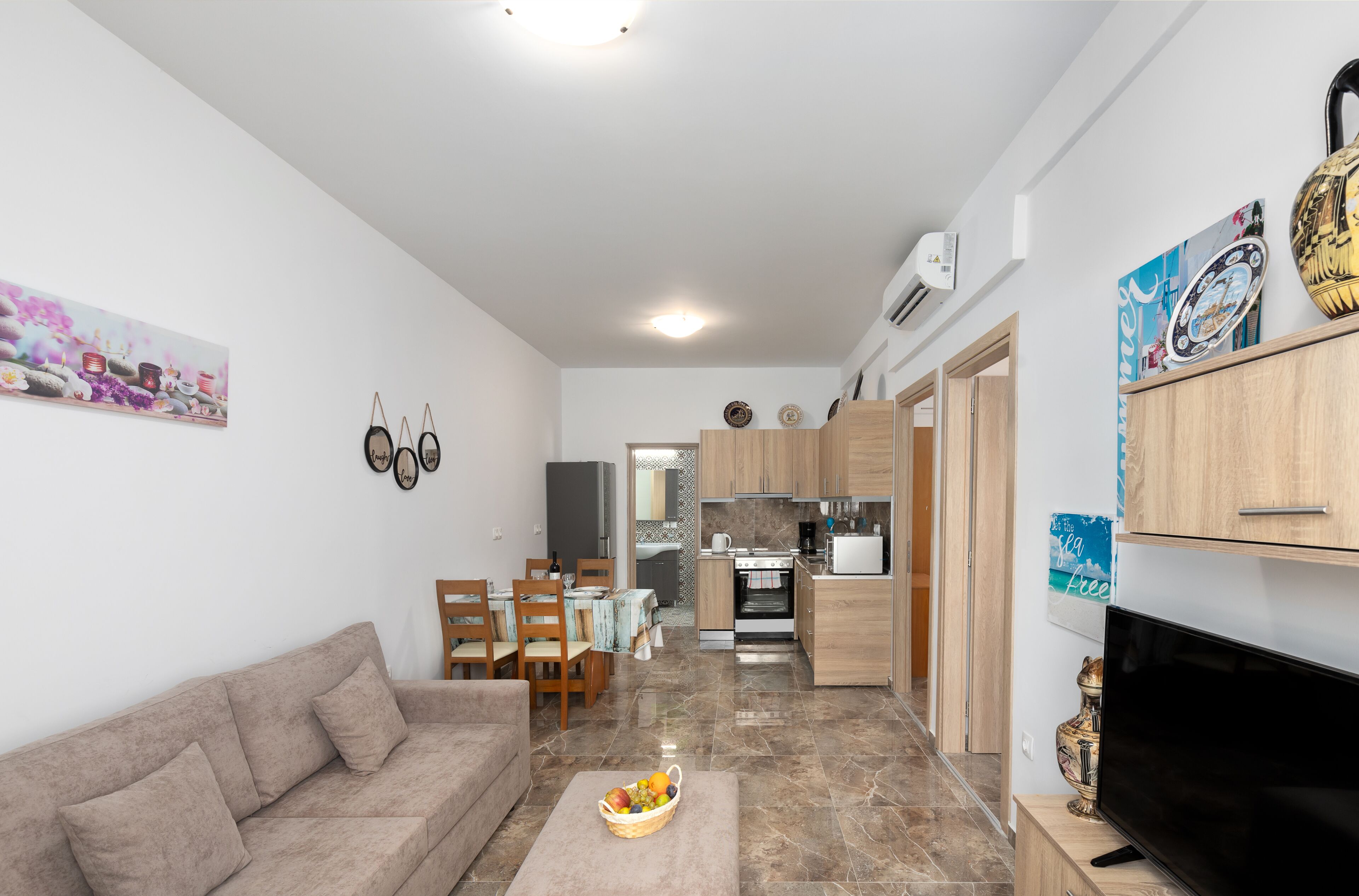 A compact living space with a sofa, dining area, kitchen, and a flat-screen TV.