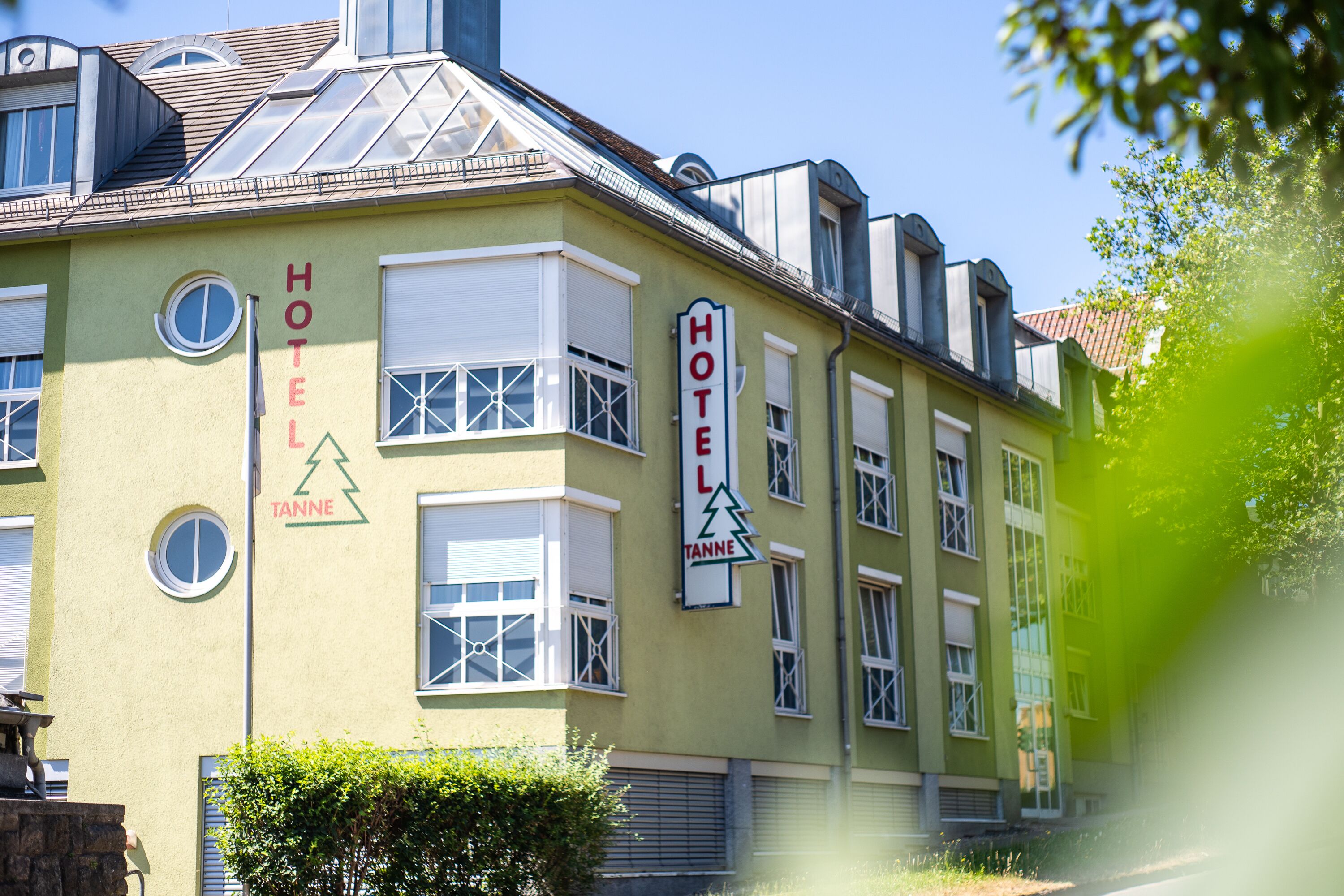 A hotel building with a green facade, multiple windows, and a sign indicating it is a hotel.