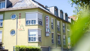 A hotel building with a green facade, multiple windows, and a sign indicating it is a hotel.