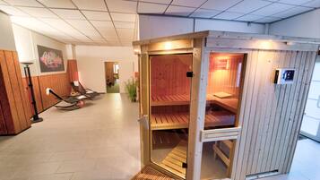 Una sala de sauna con bancos de madera y una puerta de cristal.