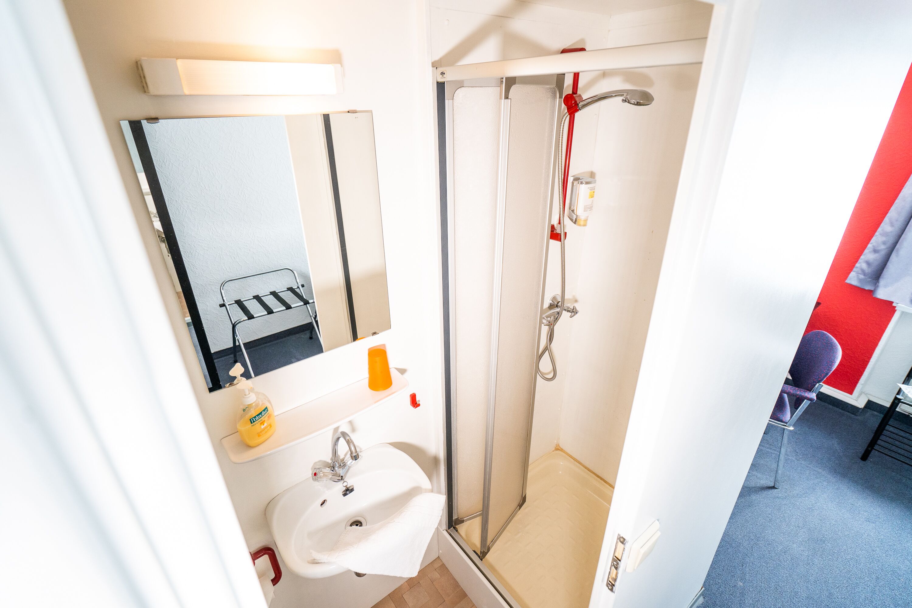A bathroom with a white sink, mirror, and shower.