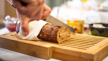 A loaf of bread being sliced on a wooden cutting board.