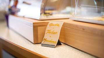 A sign with the text "Gauda Tilsiter Maasdammen" on a wooden counter.