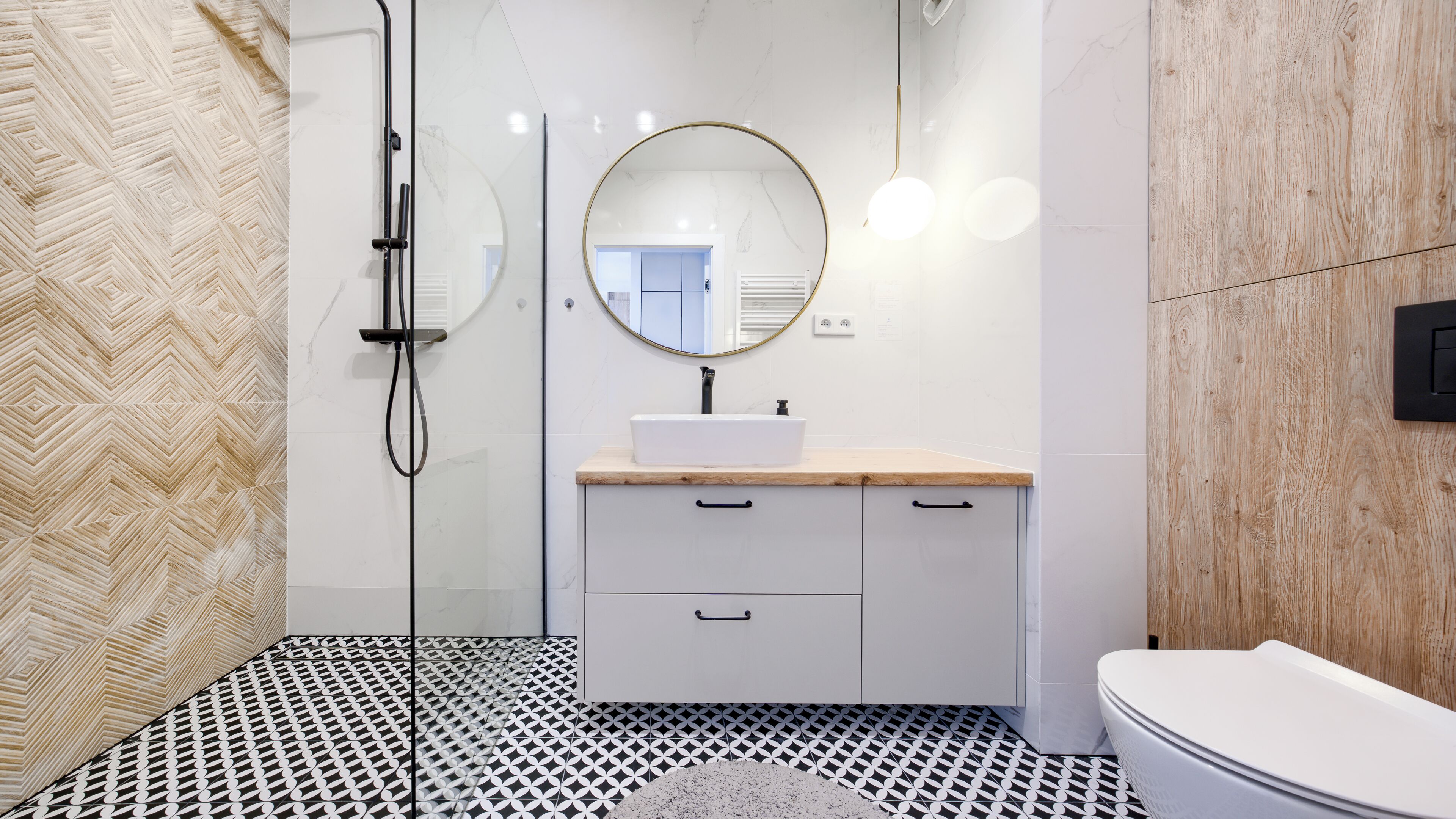 Une salle de bain moderne avec un lavabo rectangulaire, un miroir rond et une cabine de douche.