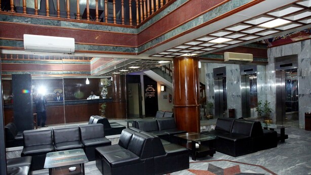 Eine Lobby mit schwarzen Ledersitzmöbeln, Marmorböden und einem geometrisch gemusterten Teppich.