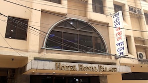 Ein mehrstöckiges Hotel mit einem markanten Bogenportal und einem Schild mit der Aufschrift 'Hotel Royal Palace'.