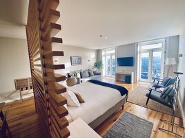 Un dormitorio moderno con una cama grande, un televisor y un balcón con vista a la ciudad.