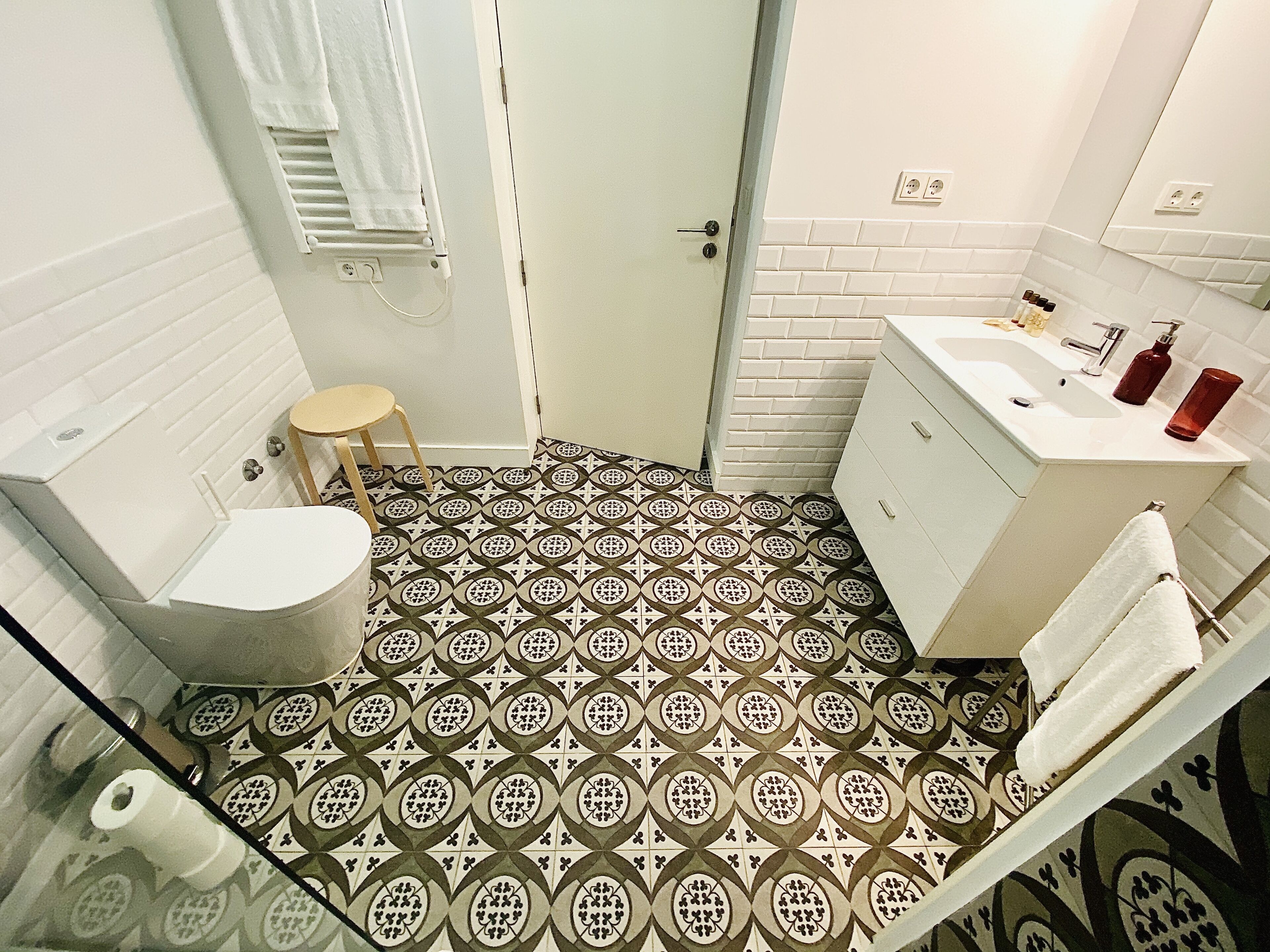 A bathroom with a patterned floor, a toilet, a sink, and a mirror.