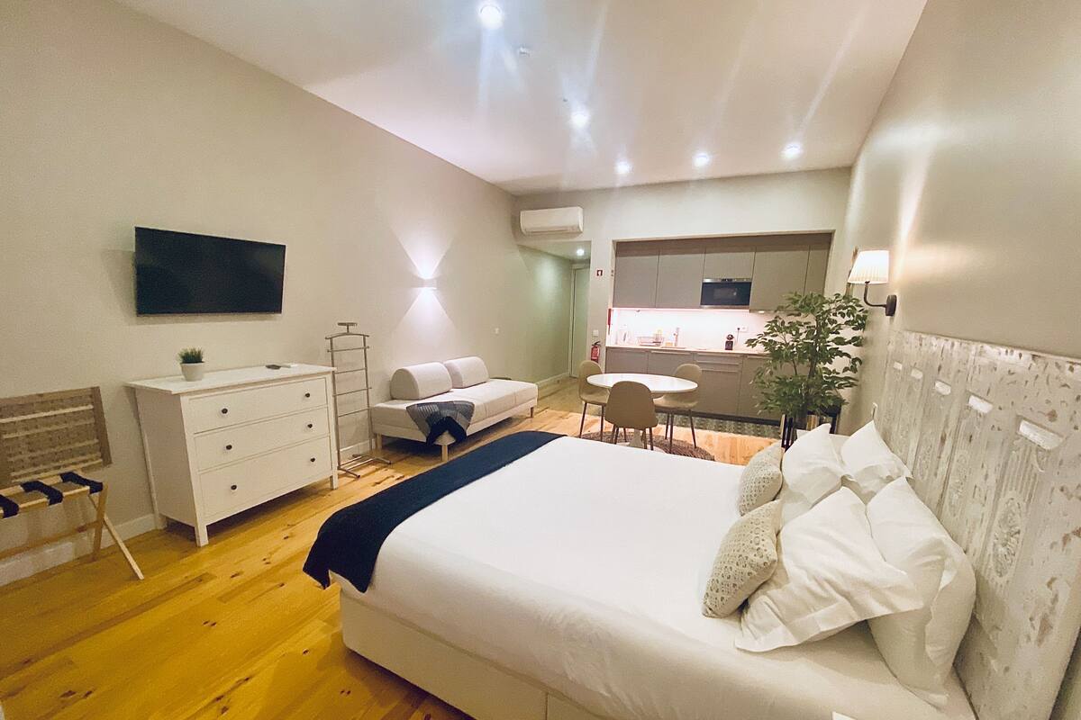 A bedroom with a bed, bedside table, dresser, and a small seating area with a sofa and chairs.