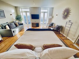 Un salón amplio con una cama grande, un sofá y un televisor.