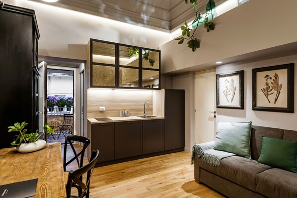 A modern kitchen with a wooden dining table and chairs, a built-in sink, and a large mirror above the counter.
