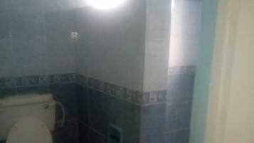 A bathroom with a toilet and bidet, tiled walls, and a visible plumbing fixture.