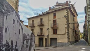 A narrow street with a building featuring balconies and a large mural on the left. - Ca la iaia - Village house in the old town of Amer (Amer)