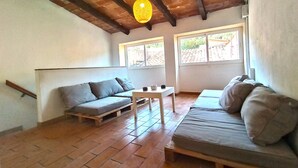 A cozy room with a wooden floor, two sofas, a small table, and a hanging light fixture. - Ca la iaia - Village house in the old town of Amer (Amer)