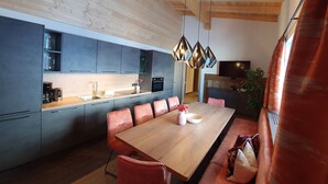 Una cocina moderna con armarios grises, una mesa de comedor de madera y una lámpara colgante.