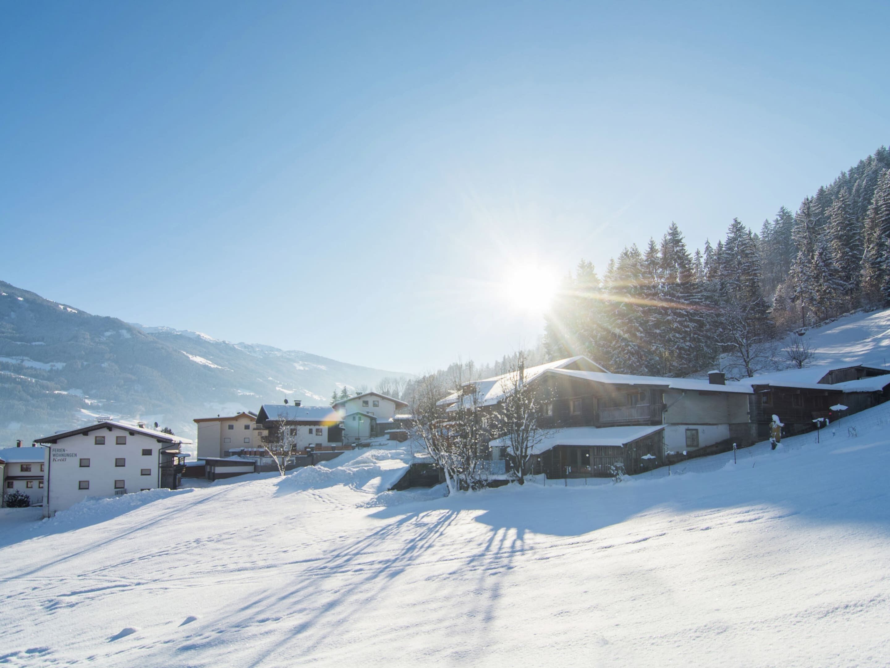 A snow-covered village with buildings and a mountain backdrop.