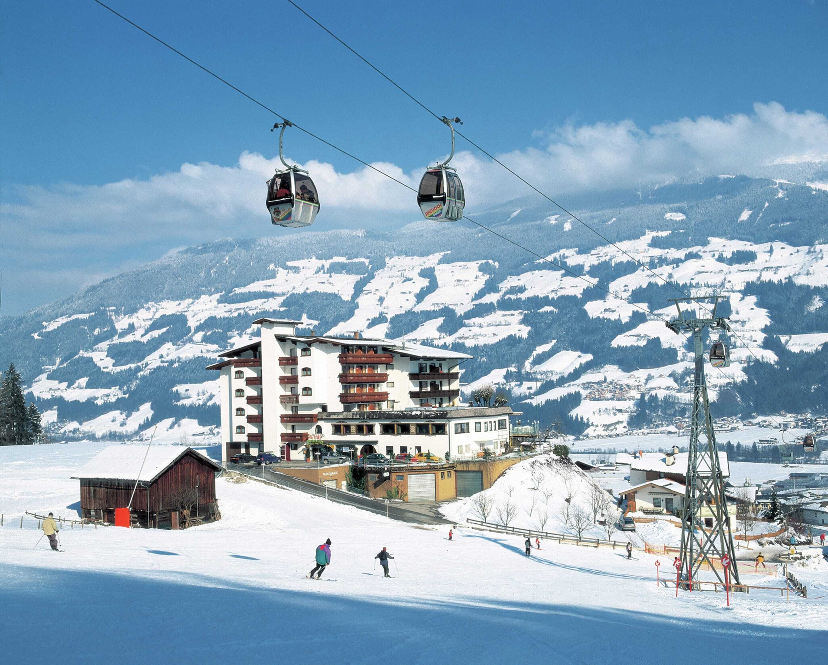 A ski resort with a building featuring multiple balconies and a ski lift in the background.