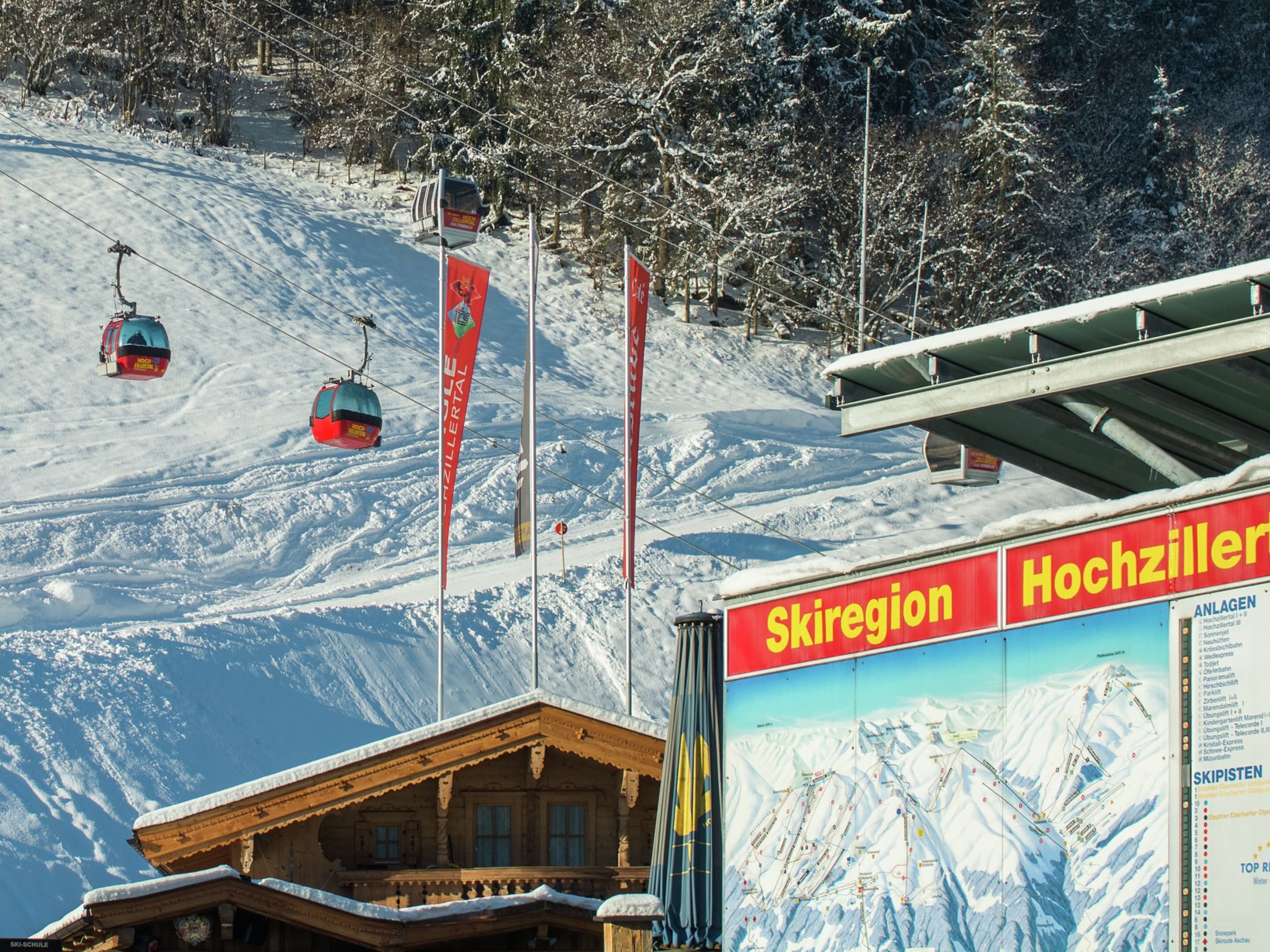 Een wintersportgebied met een houten gebouw, skiliften en een bordje met 'Skiregion Hochzillern'.