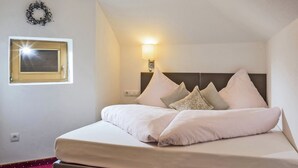 Ein Hotelzimmer mit einem Bett, einer Wandleuchte, einem Fenster mit Jalousien und einem Zierkranz.