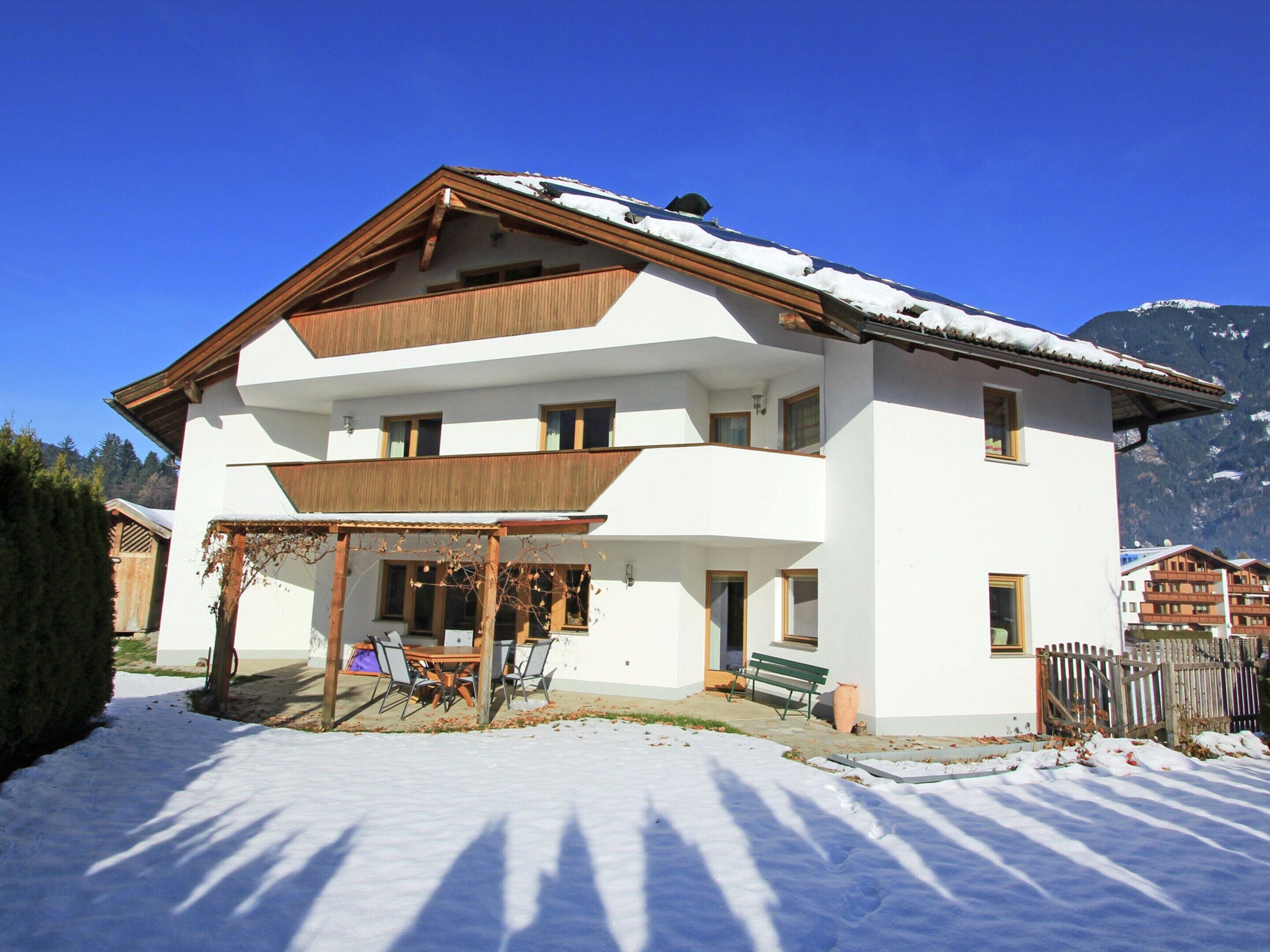 A two-story building with a balcony, a covered outdoor seating area, and a snow-covered roof.