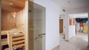 A sauna room with wooden benches and a glass door, a tiled hallway with a bench, and a door with an exit sign. - Holiday Home in Kaltenbach Near ski Lift (Stumm)