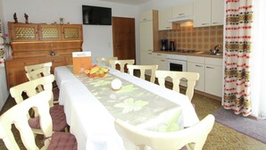 A dining area with a long table, chairs, a kitchen in the background, and a sign that reads "Belvilla". - Chalet in Aschau Near Ski Bus & Zillertal Slopes (Aschau Im Zillertal)