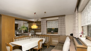 A cozy, well-lit dining area with a wooden table and chairs, a bench, and a sofa. - Heavenly Apartment in Wängle Tyrol near Walking Trails (Waengle)