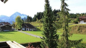 A rural landscape with a house, a wooden deck, and a mountain in the background. - Heavenly Apartment in Wängle Tyrol near Walking Trails (Waengle)