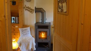 A cozy room with a wood-burning stove, a sign reading "Home where my heart is," and a hanging decoration of a deer.