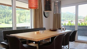 Un comedor moderno con una mesa de madera, sillas negras y lámparas colgantes.