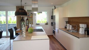 Una cocina moderna con una isla central, electrodomésticos de acero inoxidable y vistas al exterior.