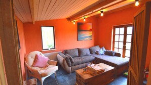 Een gezellige woonkamer met een bank, fauteuil en houten bijzettafeltje.