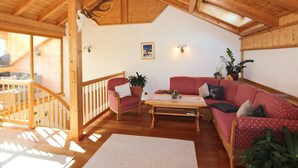 Un interno in legno con un divano rosso, un tavolino in legno e un soffitto decorato con una testa di cervo.