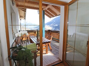 A wooden deck with a table and chairs, overlooking a mountainous landscape. - Holiday Home in Wenns Tyrol (Wenns)
