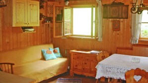 A wooden cabin interior with a sofa, a table, a cabinet, and a window with curtains. - Chalet in Kolbnitz Near Ski Slopes (Reisseck)