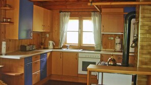 A wooden cabin-style kitchen with a stove, sink, and cabinets. - Chalet in Kolbnitz Near Ski Slopes (Reisseck)