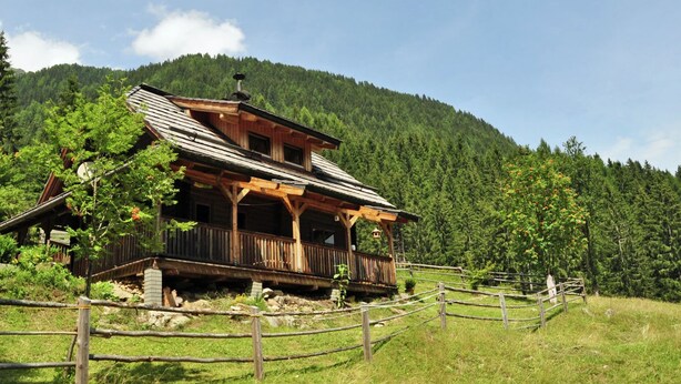 A wooden cabin with a balcony, surrounded by a wooden fence, set in a forested mountainous area. - Chalet in Kolbnitz Near Ski Slopes (Reisseck)