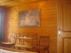 A wooden cabin interior with a bed, two wooden chairs, a small table, and a painting on the wall. - Chalet in Kolbnitz Near Ski Slopes (Reisseck)