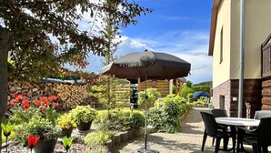 An outdoor patio with a table and chairs, surrounded by potted plants and a stone wall. - Damshagen Kustenkomfort (Damshagen)